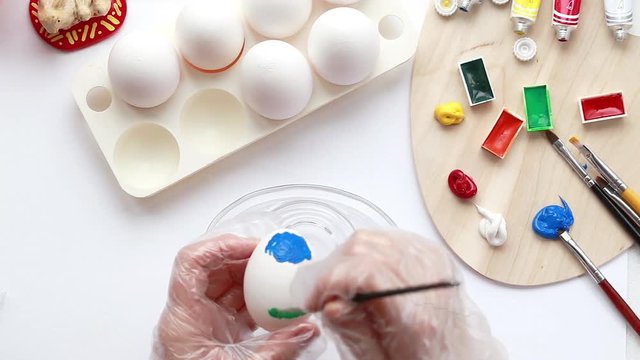 Paint eggs with colored paints with their hands. Draw a picture on the eggs for the holiday
