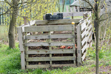 Wooden construction composter with black plastic crate.
