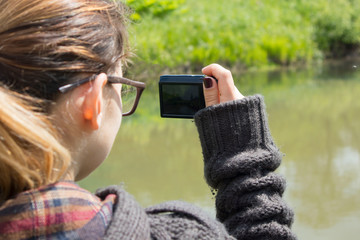 young woman takes pictures of nature near the river. girl photographer with retro camera