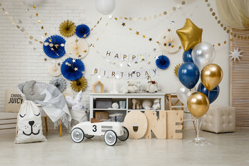 Birthday decorations with gifts, toys, garlands and figure for little baby party on a white bricks...