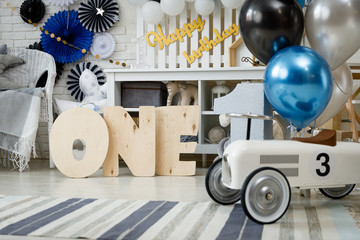 Birthday decorations with gifts, toys, garlands and figure for little baby party on a white bricks background. 