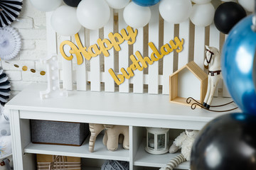 Birthday decorations with gifts, toys, garlands and figure for little baby party on a white bricks background. 