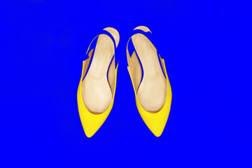 Glamor yellow fashion shoes on blue neon background. Minimal. Bright Art Colorful Style. Luxury Shiny Party lady. flat lay.