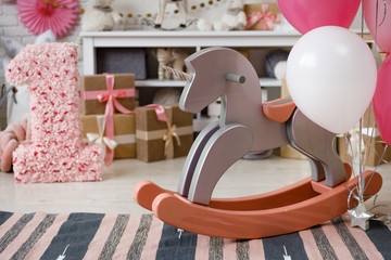 Birthday decorations with gifts, toys, garlands and figure for little baby party on a white bricks background. 