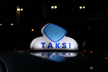 Taxi light sign or cab sign in blue and white color on the car roof at the street in the dark night.