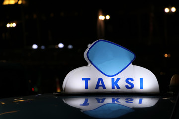 Taxi light sign or cab sign in blue and white color on the car roof at the street in the dark night.