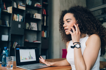young brunette woman having business call and working in modern office with laptop