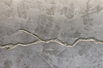 The texture of the gray concrete wall is decorated with a deep crack of silver color.