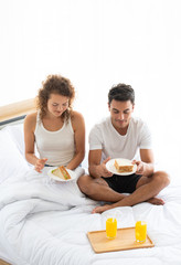 Obraz na płótnie Canvas Happy couples relaxing in the white bedroom Of the apartment With various emotions With snacks, coffee, fruit in the morning