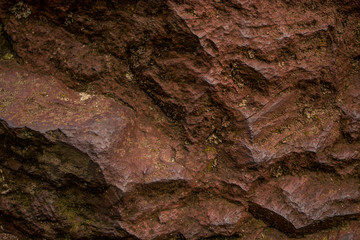 Background or texture from a red stone with cracks and the broken-away parties with an impregnation a moss. Natural material.