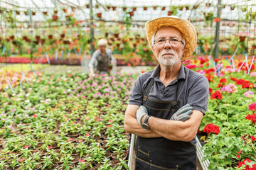 Confident mature greenhouse owner with arms crossed.