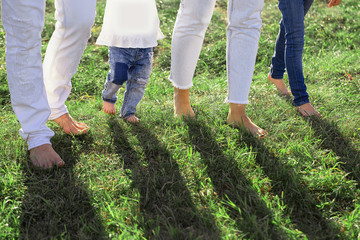 Father, mother, son and daughter walking along the path. Family feet and legs in jeans.