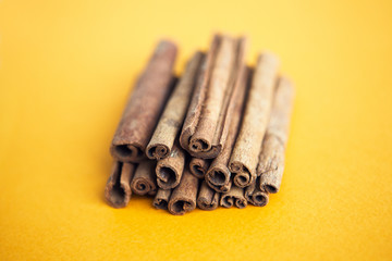 Set of cinnamon sticks on yellow background