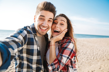 Shocked young loving couple outside in free alternative vacation camping take selfie by camera.