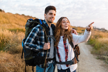 Happy young loving couple outside with backpack in free alternative vacation camping.