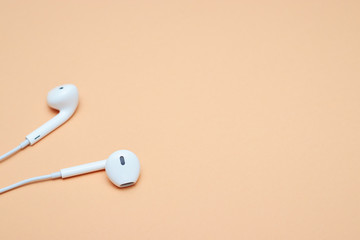 Headphones on a pastel background. White headphones on a peach background. View from above. Copy space Trendy colorful photo. Minimal style with colorful paper background. Music concept