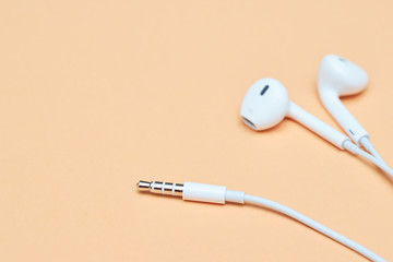 Headphones on a pastel background. White headphones on a peach background. View from above. Copy space Trendy colorful photo. Minimal style with colorful paper background. Music concept