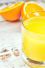 Fresh orange juice in a glass and orange slices on a light wooden table. vertical view. detox. close-up. citrus summer refreshing drink.