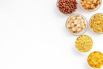 Various corn cereals in bowls on white background top view copyspace