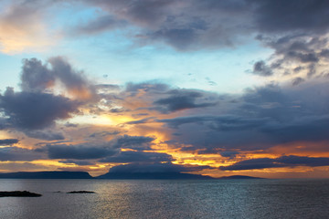 Sunset through storm clouds over the Inner Hebridean islands of Rum and Eigg off the west coast of Scotland. Photographed from a rocky headland at Portnaluchaig 56° 56` 22.11