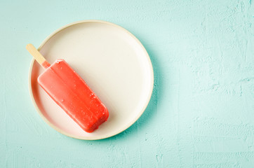 ice cream. Homemade red glaze  ice cream on a stick in white bowl on a turquoise background. Top view and copy space. Sweet dessert closeup