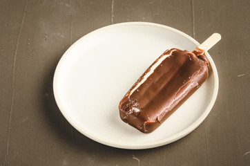 ice cream. Homemade dark chocolate ice cream on a stick in white bowl. Dark background. Sweet dessert closeup
