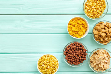 cereals, oatflakes and cornflakes for healthy breakfast on mint wooden background top view mock up