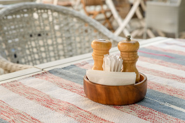 wooden stand with pepper, salt shaker, napkins and toothpicks on the table of the summer terrace of the restaurant