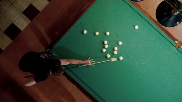 Top view of man playing billiards, hitting the balls with a cue into pockets on a billiard table. 4K