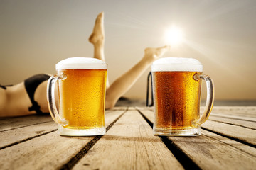 Cold beer on wooden pier and summer sunset time. Slim young woman legs and free space for your decoration. 