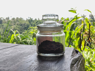 glass coffee jar isolated on the table with coffee estate in  the background