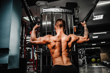 Fototapeta na wymiar Strong Bodybuilder Doing Heavy Weight Exercise For Back On Machine.