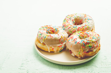 Donats. A plate with appetizing donata in white glaze. Fresh pastries.