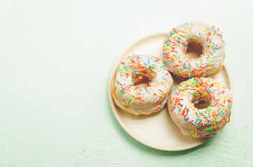 Donats. A plate with appetizing donata in white glaze. Fresh pastries. Top view and copy space.