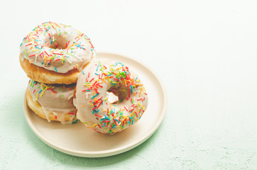 Donats. A plate with appetizing donata in white glaze. Fresh pastries. Copy space.