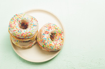 Donats. A plate with appetizing donata in white glaze. Fresh pastries. Top view and copy space.