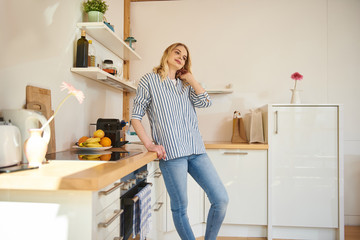 Beautiful young woman standing in kitchen at home