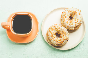 Сoffee break. Orange cup with coffee and a plate from donata in white glaze with nuts. Top view