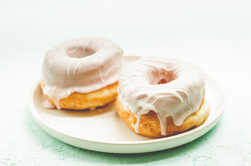 Donats in white glaze. Fresh pastries. A plate from donats in white glaze. Sweet food concept.