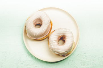 Donats in white glaze. Fresh pastries. A plate from donats in white glaze. Top view. Sweet food concept.