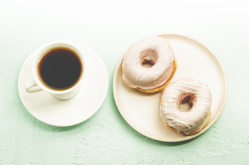 Сoffee break. White cup with black coffee and donat in glaze. Top view