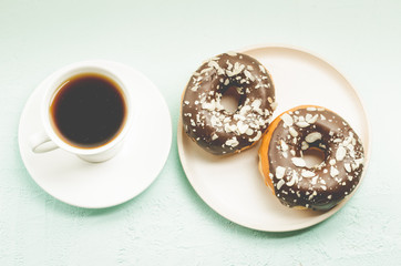 Сoffee break. White cup with black coffee and donat in chocolate glaze. Top view