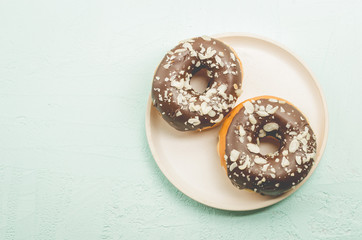 Donats. A plate with appetizing donata in chocolate glaze. Top view and copyspace. Fresh pastries.