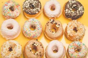 Colorful donut pattern on yellow background. Sweet food concept. Top view