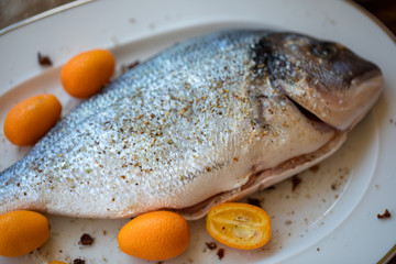 Preparation for roasting in an oven of fresh fish the Gilthead strewed with spices. Soft focus. Easy degradation. Macro.