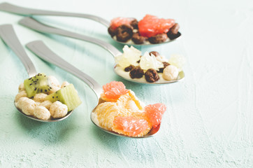 Healthy Breakfast. Dry breakfast with fruit in spoons on a blue background