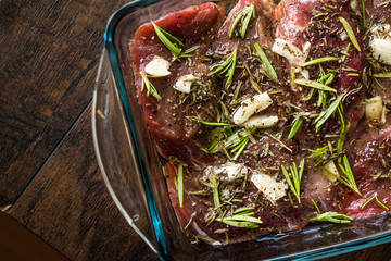 Marinated Raw Tenderloin Meat with Rosemary, Garlic and Olive Oil in Glass Bowl Ready to Cook.