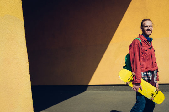 Young hipster man walking with skateboard outdoor