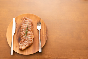 Fresh cooked beef sirloin steak with rosemary on wood plate, Wood background, Copy space on the right