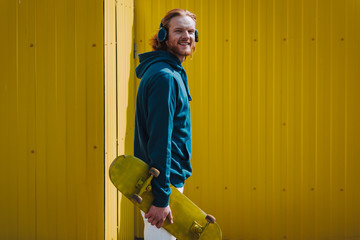 Young happy hipster man on yellow fence view